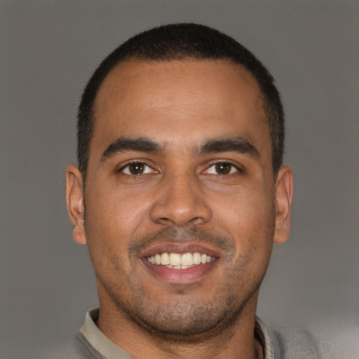 Joyful black young-adult male with short  brown hair and brown eyes