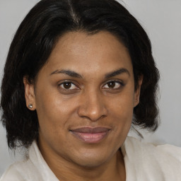 Joyful black adult female with medium  brown hair and brown eyes