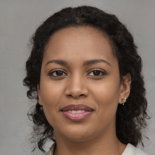 Joyful black young-adult female with long  brown hair and brown eyes