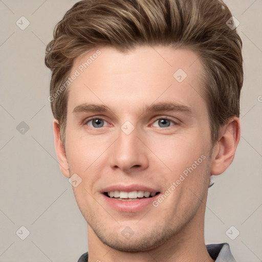 Joyful white young-adult male with short  brown hair and grey eyes