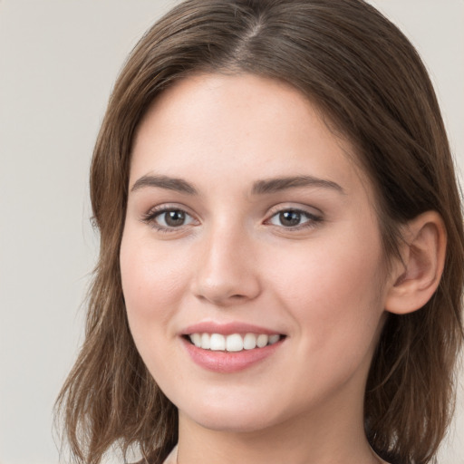 Joyful white young-adult female with long  brown hair and grey eyes