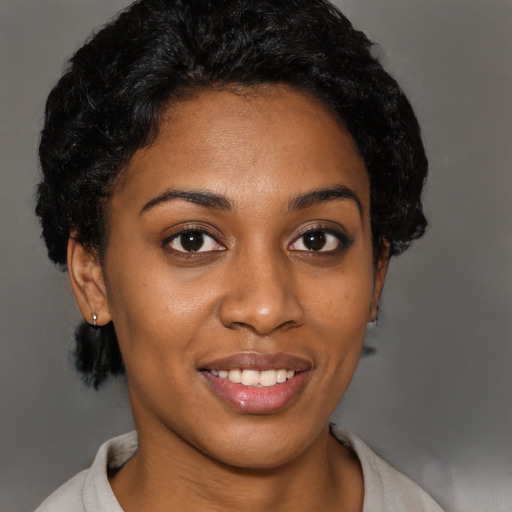 Joyful black young-adult female with short  black hair and brown eyes