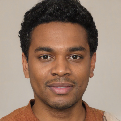 Joyful black young-adult male with short  black hair and brown eyes