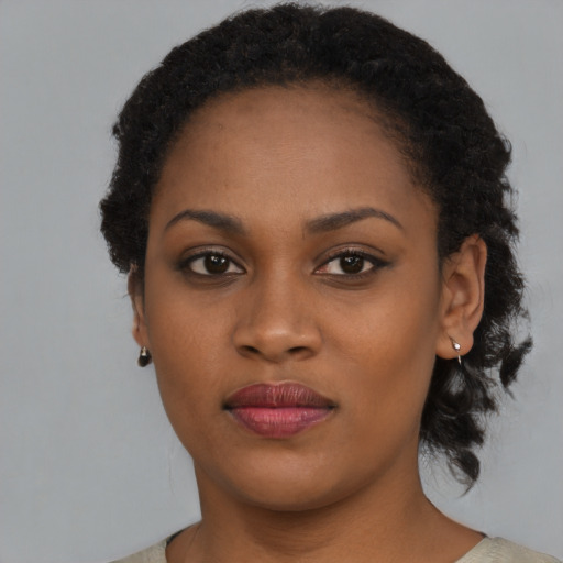 Joyful black young-adult female with short  black hair and brown eyes