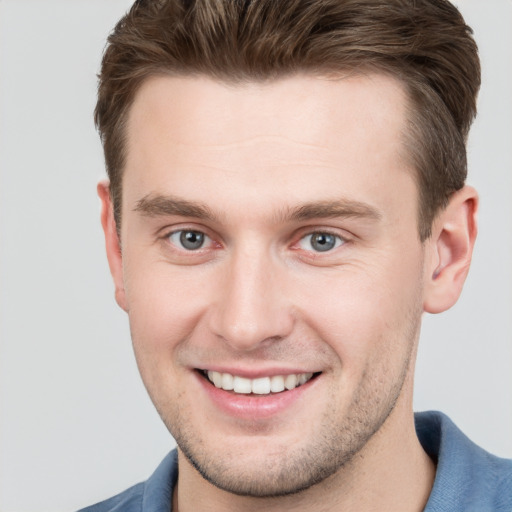 Joyful white young-adult male with short  brown hair and grey eyes