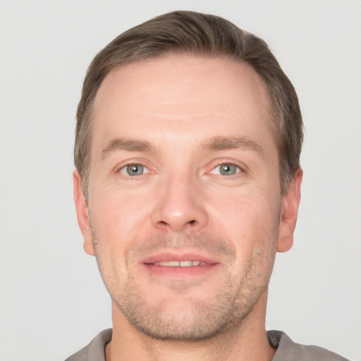 Joyful white young-adult male with short  brown hair and grey eyes