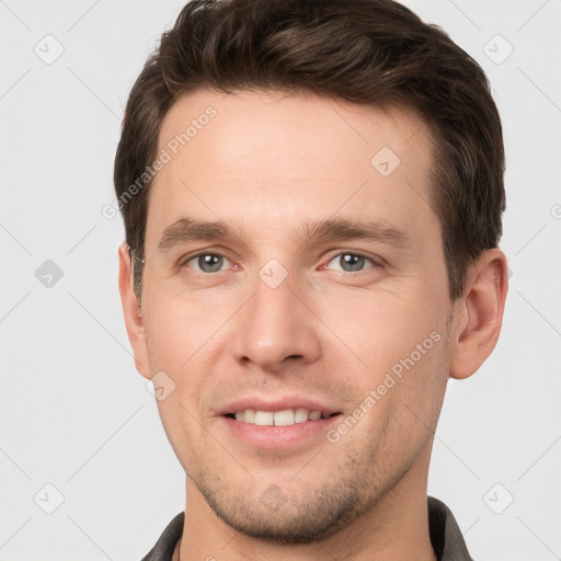 Joyful white young-adult male with short  brown hair and grey eyes