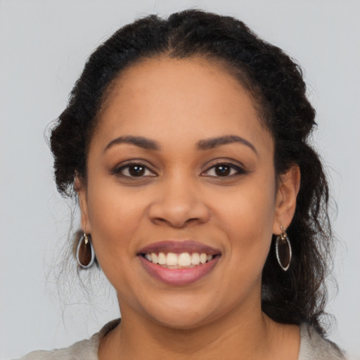 Joyful black young-adult female with long  brown hair and brown eyes