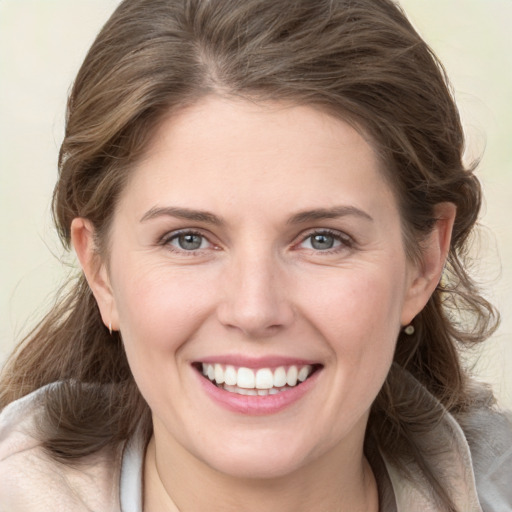 Joyful white young-adult female with medium  brown hair and grey eyes