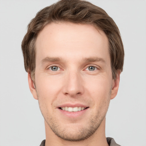 Joyful white young-adult male with short  brown hair and grey eyes