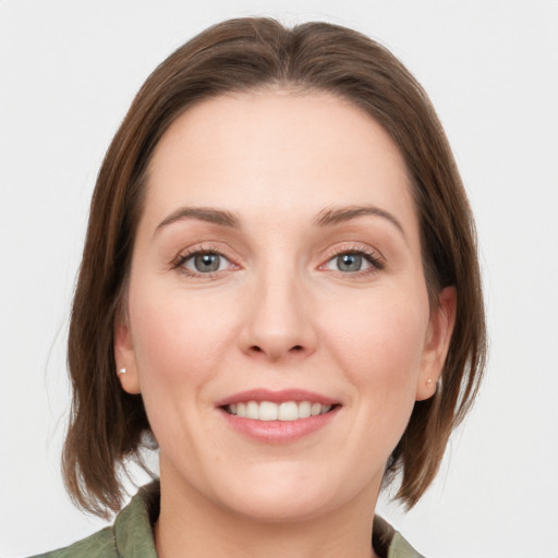 Joyful white young-adult female with medium  brown hair and grey eyes