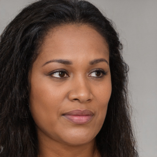 Joyful black young-adult female with long  brown hair and brown eyes