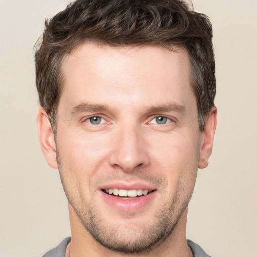 Joyful white young-adult male with short  brown hair and grey eyes