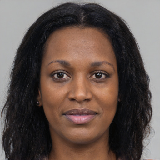 Joyful black young-adult female with long  black hair and brown eyes