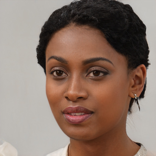 Joyful black young-adult female with short  black hair and brown eyes