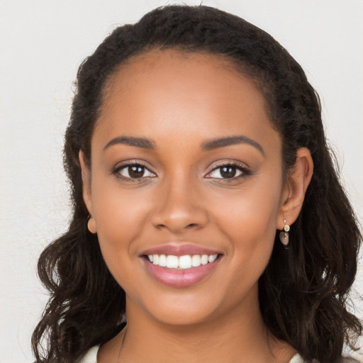 Joyful black young-adult female with long  brown hair and brown eyes