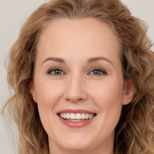 Joyful white young-adult female with long  brown hair and blue eyes