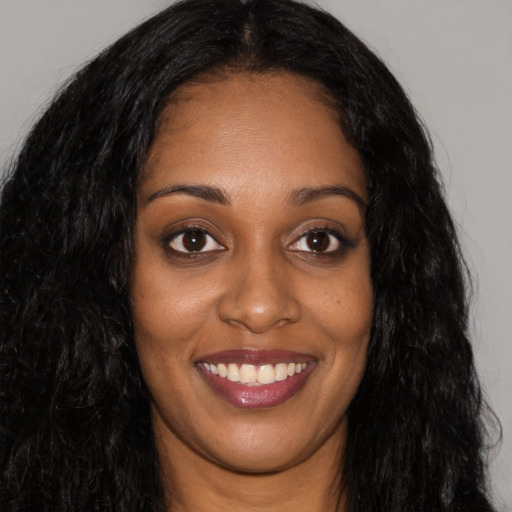 Joyful black young-adult female with long  black hair and brown eyes