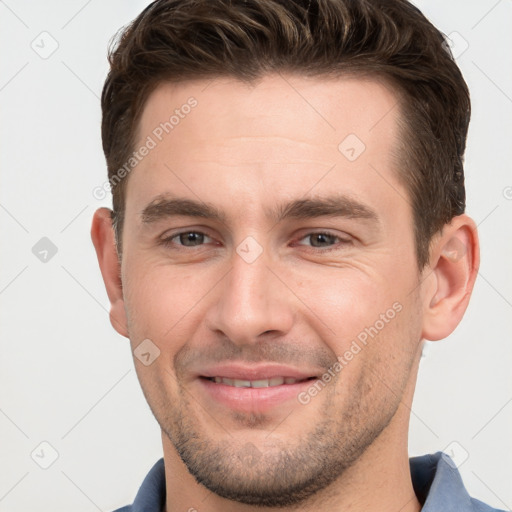 Joyful white young-adult male with short  brown hair and grey eyes