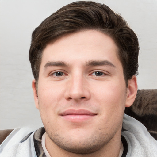 Joyful white young-adult male with short  brown hair and grey eyes