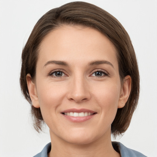 Joyful white young-adult female with medium  brown hair and grey eyes