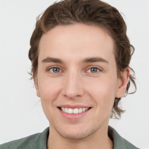 Joyful white young-adult male with medium  brown hair and grey eyes