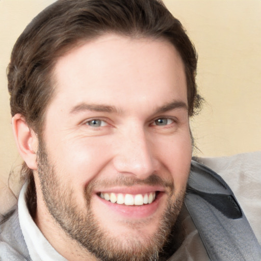 Joyful white young-adult male with short  brown hair and grey eyes