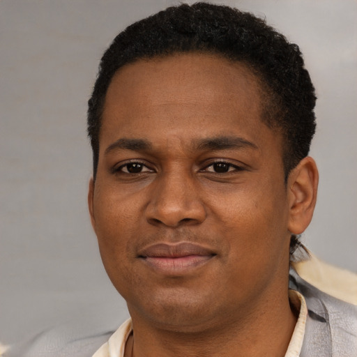 Joyful black young-adult male with short  brown hair and brown eyes