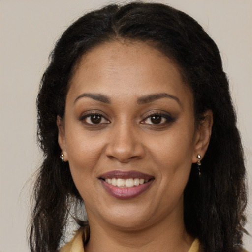 Joyful black young-adult female with long  brown hair and brown eyes