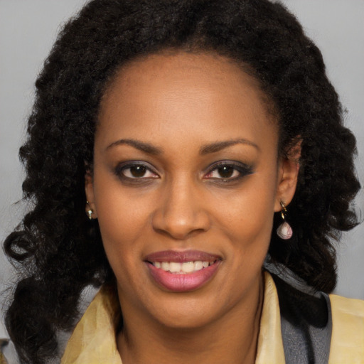 Joyful black young-adult female with long  brown hair and brown eyes
