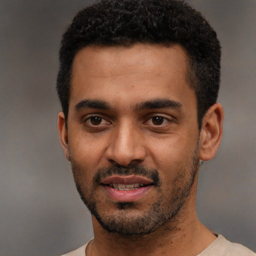 Joyful black young-adult male with short  black hair and brown eyes
