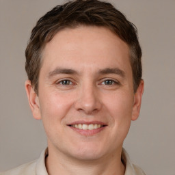 Joyful white young-adult male with short  brown hair and grey eyes