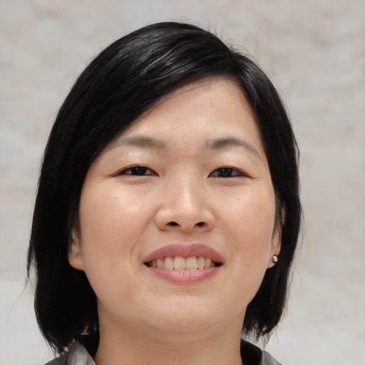 Joyful asian young-adult female with medium  black hair and brown eyes