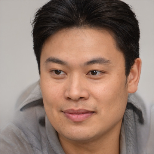 Joyful asian young-adult male with medium  brown hair and brown eyes