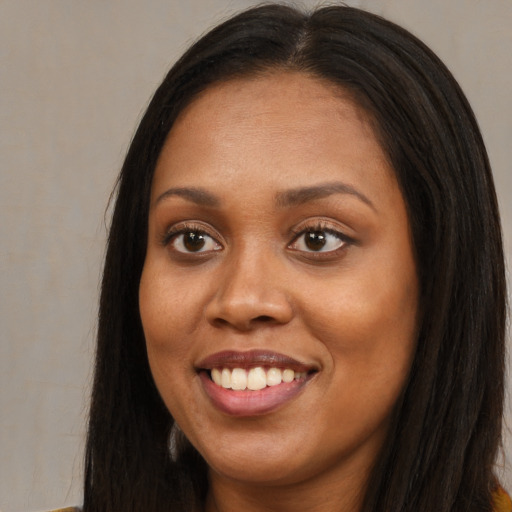 Joyful black young-adult female with long  brown hair and brown eyes