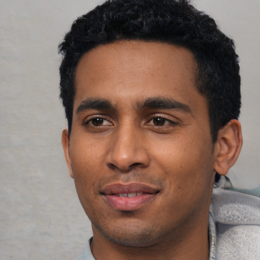 Joyful black young-adult male with short  black hair and brown eyes