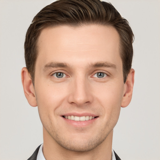 Joyful white young-adult male with short  brown hair and grey eyes