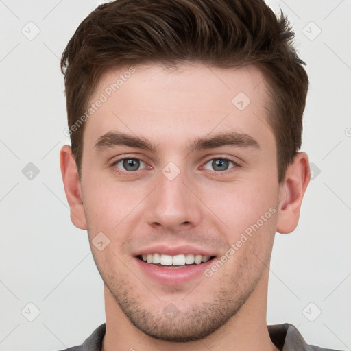 Joyful white young-adult male with short  brown hair and grey eyes