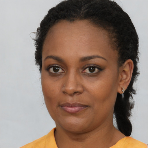 Joyful black young-adult female with long  brown hair and brown eyes