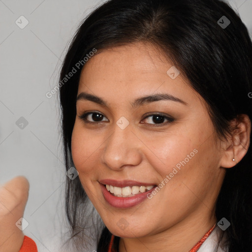 Joyful latino young-adult female with long  brown hair and brown eyes