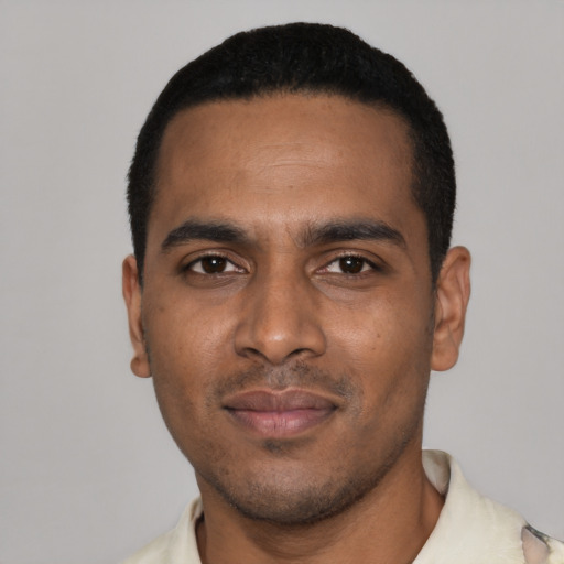 Joyful black young-adult male with short  black hair and brown eyes