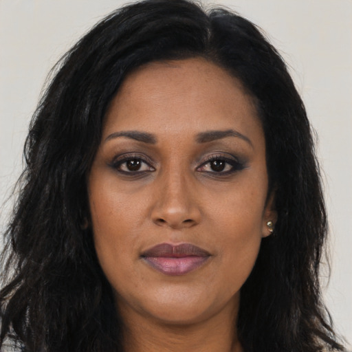 Joyful black young-adult female with long  brown hair and brown eyes