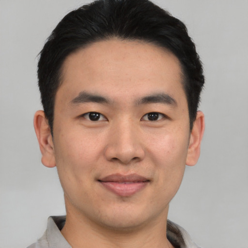 Joyful asian young-adult male with short  black hair and brown eyes