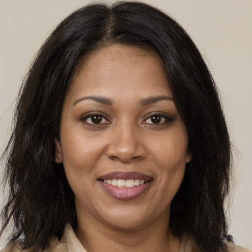Joyful black adult female with long  brown hair and brown eyes