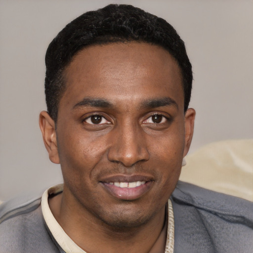 Joyful black young-adult male with short  black hair and brown eyes