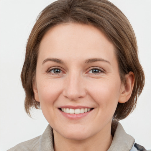 Joyful white young-adult female with medium  brown hair and grey eyes