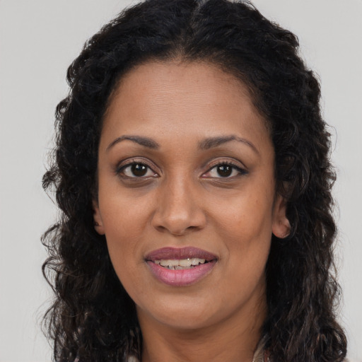 Joyful black young-adult female with long  brown hair and brown eyes