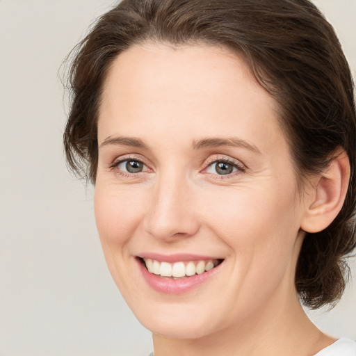 Joyful white young-adult female with medium  brown hair and green eyes