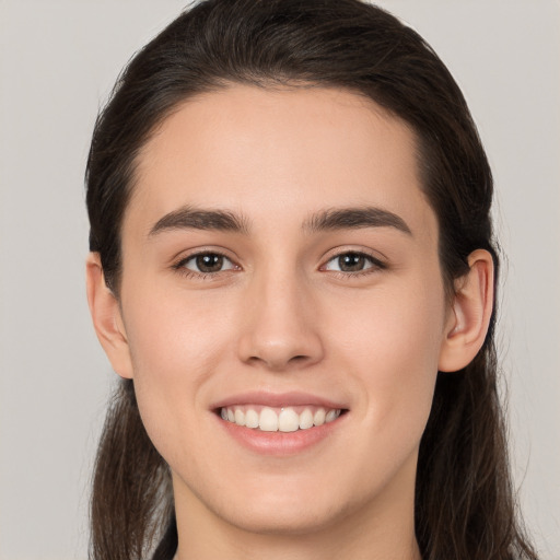 Joyful white young-adult female with long  brown hair and brown eyes