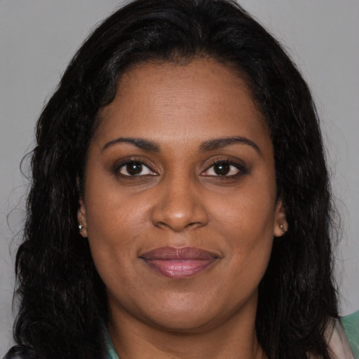 Joyful black young-adult female with long  brown hair and brown eyes
